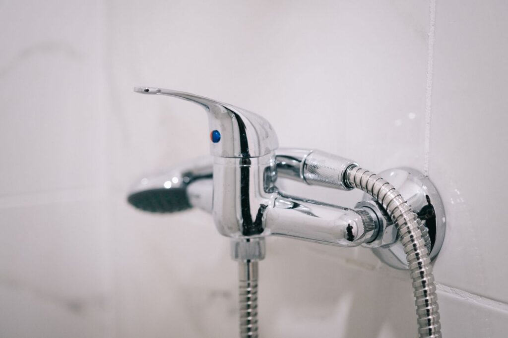 A detailed view of a sleek chrome shower faucet in a clean bathroom setting.